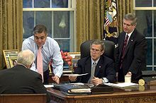 tenet left in pink tie in the oval office with president george w bush
