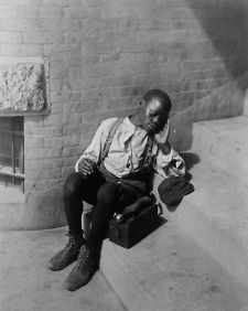 African American boy seated on steps with shoe shine box. Vintage e2